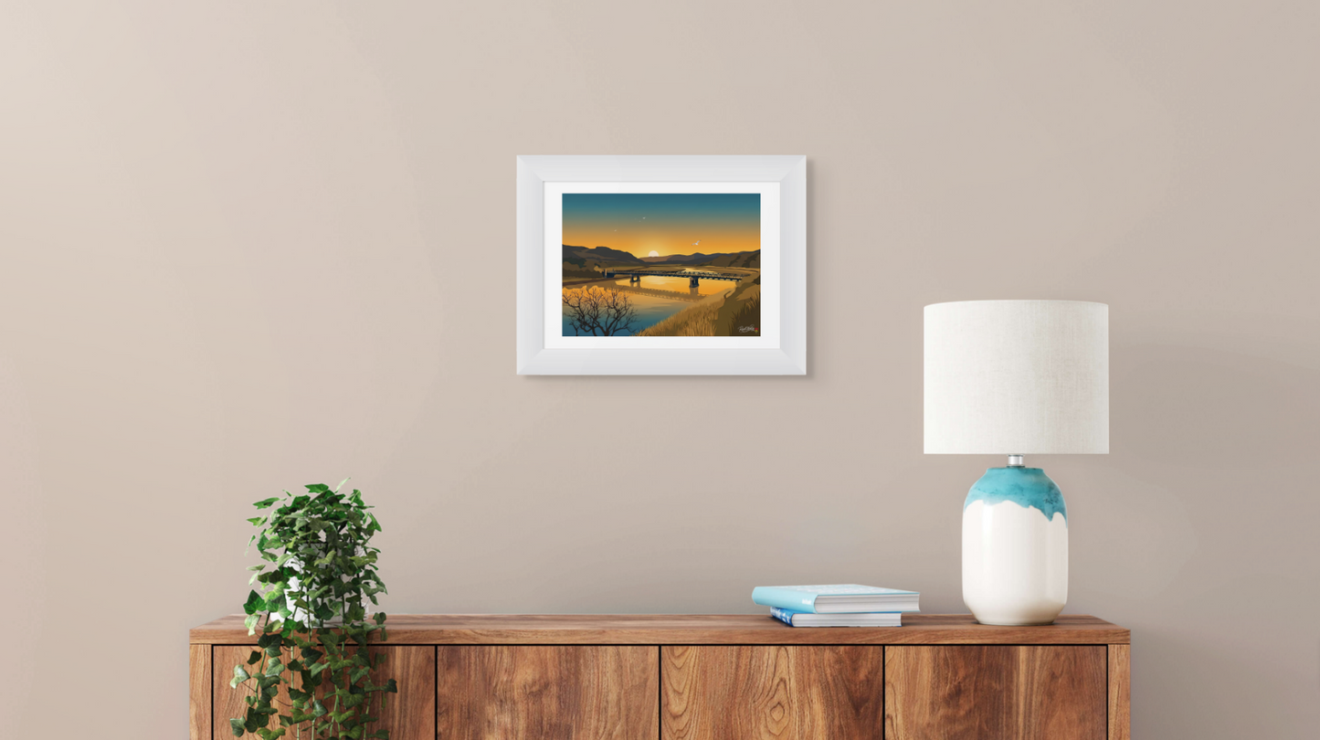 Framed artwork on a wall above a wooden sideboard with a lamp and books.